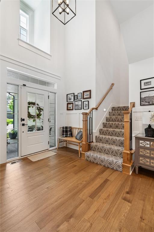 2704 W 74th St, Prairie Village, KS 66208 - foyer entrance featuring high vaulted ceiling, wood finished floors, stairs, and a chandelier