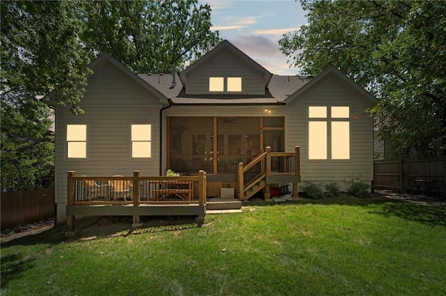 2704 W 74th St, Prairie Village, KS 66208 - back of house at dusk featuring a sunroom, roof with shingles, and a deck