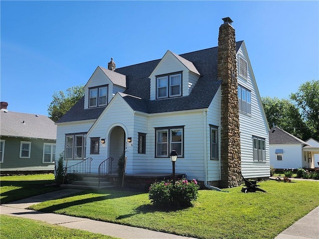 cape cod home featuring a chimney, a front yard, and roof with shingles