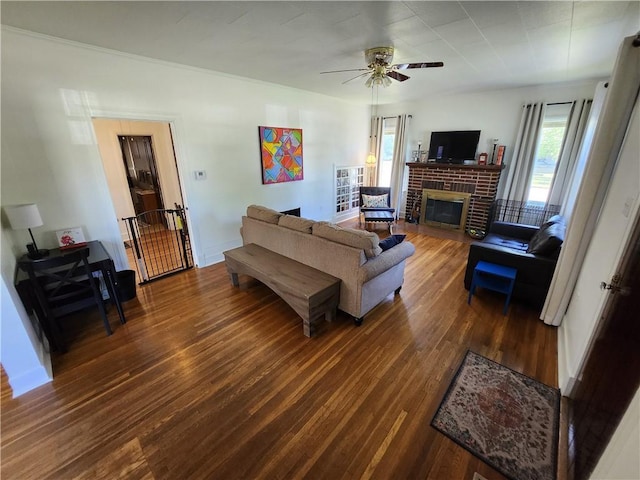 living room with a ceiling fan, a brick fireplace, baseboards, and wood finished floors
