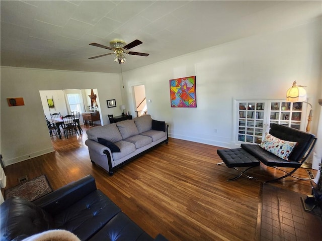 living room featuring wood finished floors, visible vents, baseboards, and a ceiling fan