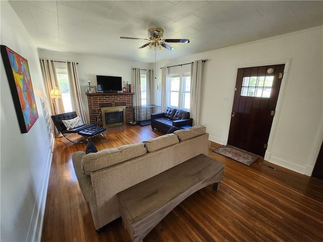 living area with a fireplace, a wealth of natural light, hardwood / wood-style floors, and a ceiling fan
