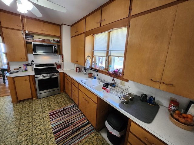 kitchen featuring a ceiling fan, a sink, brown cabinets, light countertops, and appliances with stainless steel finishes