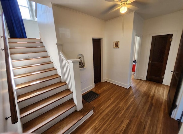 staircase featuring wood finished floors, visible vents, crown molding, a ceiling fan, and baseboards
