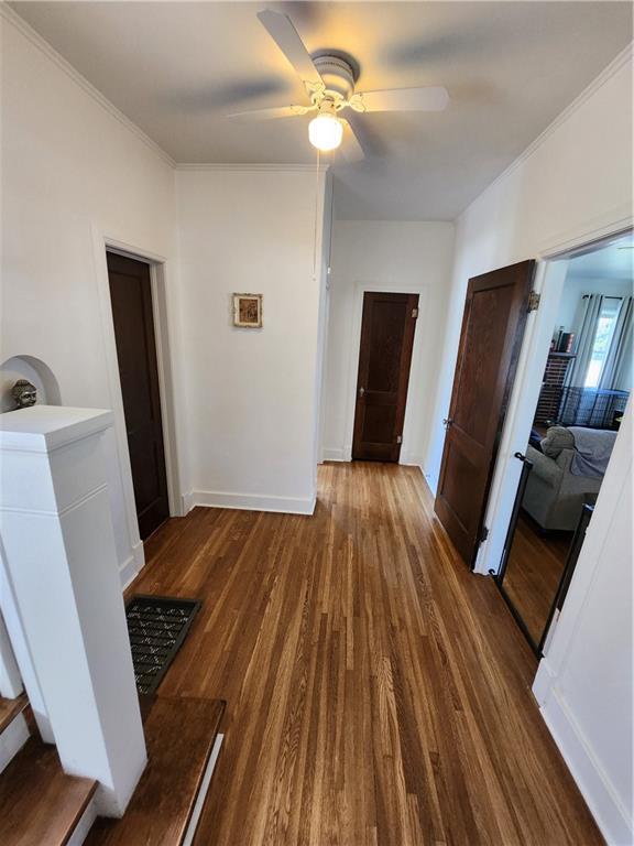hall featuring crown molding, wood finished floors, and baseboards