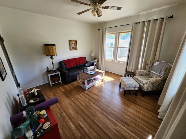 living area with a ceiling fan, baseboards, and wood finished floors