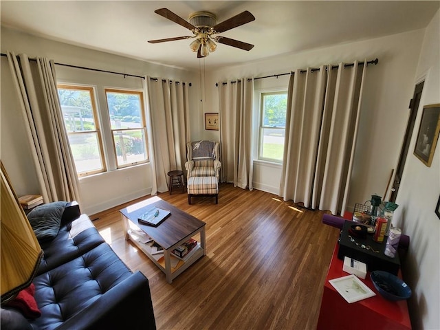 living area featuring a ceiling fan, baseboards, and wood finished floors