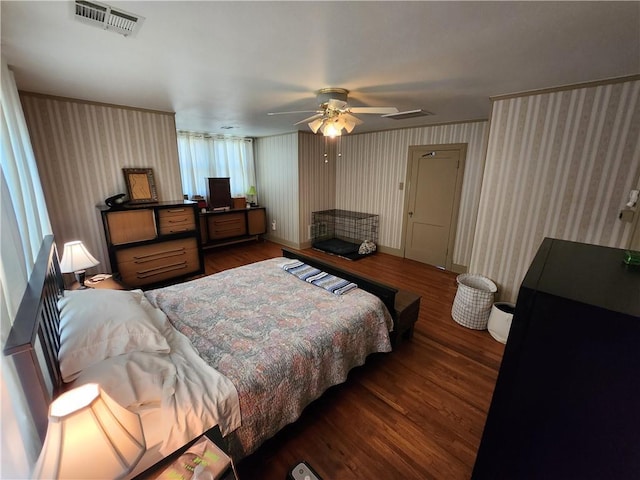 bedroom featuring a ceiling fan, wallpapered walls, baseboards, visible vents, and wood finished floors