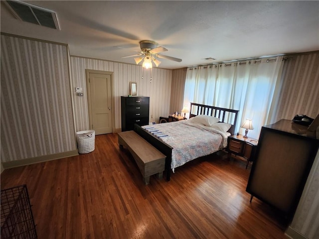 bedroom with a ceiling fan, wallpapered walls, visible vents, and dark wood-style floors