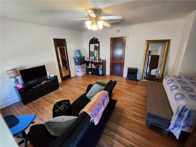 living area with crown molding, wood finished floors, and ceiling fan