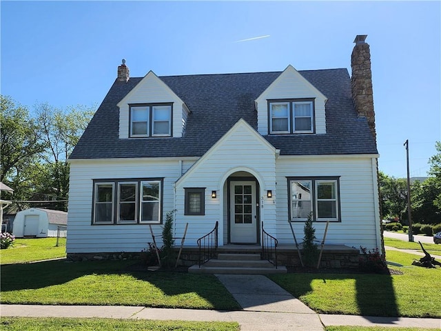 cape cod home with a chimney, entry steps, and a front lawn