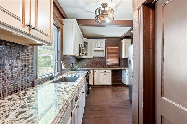 2803 Harrison St, Kansas City, MO 64109 - kitchen featuring a sink, stainless steel appliances, decorative backsplash, dark wood-style flooring, and light stone countertops