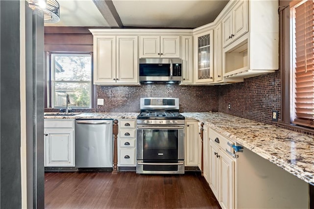 2803 Harrison St, Kansas City, MO 64109 - kitchen featuring stainless steel appliances, a sink, cream cabinets, dark wood-style flooring, and tasteful backsplash