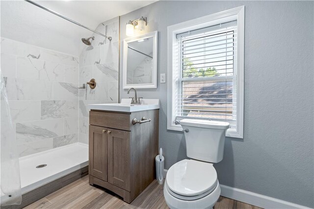 2803 Harrison St, Kansas City, MO 64109 - full bath with wood finished floors, a tile shower, toilet, and vanity