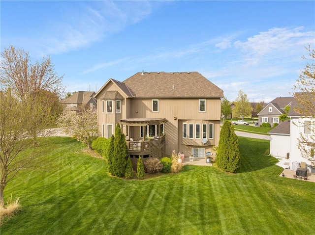 back of house featuring a wooden deck, a pergola, a lawn, a patio, and roof with shingles