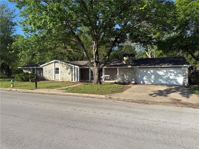 view of front of house featuring an attached garage, stone siding, and driveway