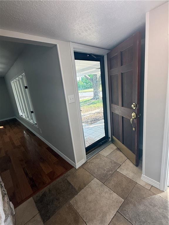 foyer entrance with baseboards and a textured ceiling