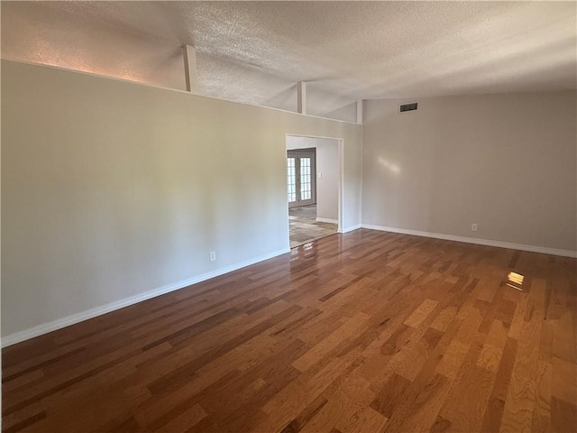unfurnished room with baseboards, visible vents, a textured ceiling, and wood finished floors