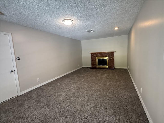 unfurnished living room with a textured ceiling, baseboards, dark colored carpet, visible vents, and a fireplace