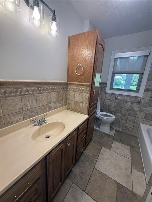 full bathroom featuring tile walls, toilet, vanity, wainscoting, and a bathing tub