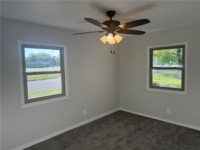 empty room with baseboards, a ceiling fan, and dark carpet