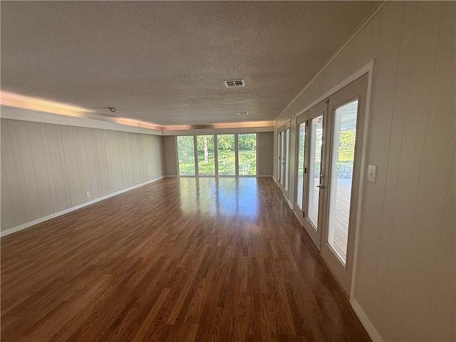 interior space featuring a textured ceiling, visible vents, dark wood-style flooring, and baseboards