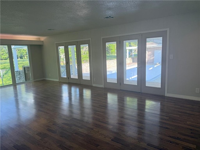 unfurnished living room with dark wood-style floors, french doors, visible vents, and a textured ceiling