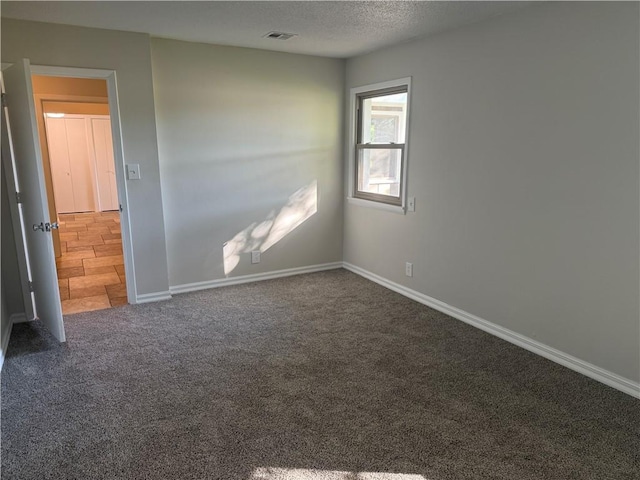 carpeted empty room with baseboards, visible vents, and a textured ceiling