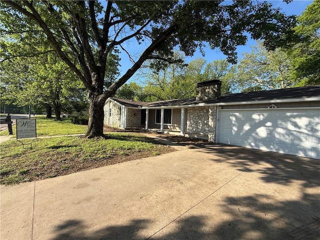 view of front of house with concrete driveway, a chimney, a garage, and stone siding