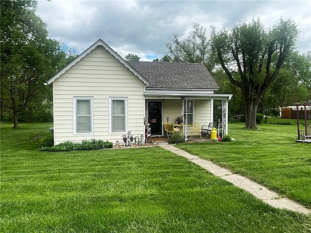 view of front facade featuring a porch, roof with shingles, and a front lawn