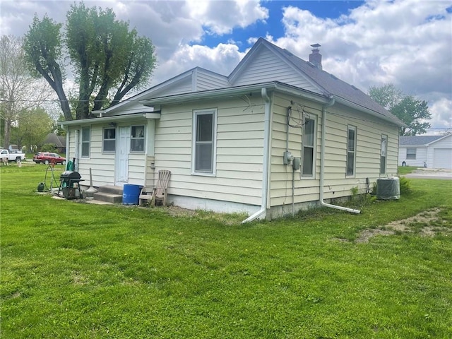 view of side of home featuring a yard, a chimney, and central air condition unit