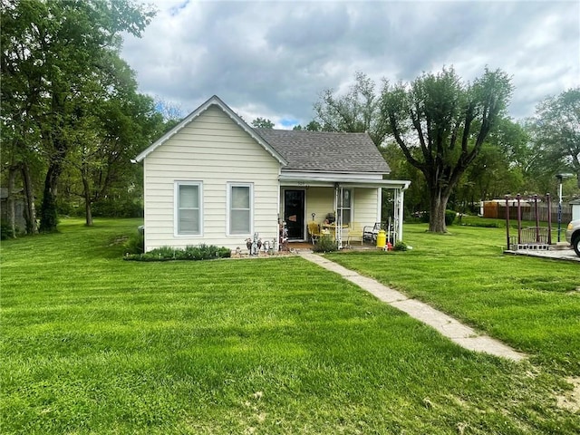 back of house with a lawn, a porch, and roof with shingles