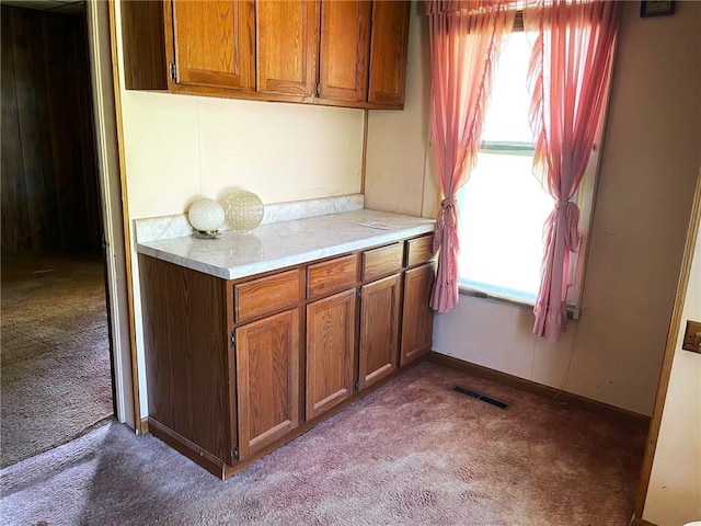 509 Whitcomb St, Lathrop, MO 64465 - kitchen with carpet, brown cabinetry, and light countertops