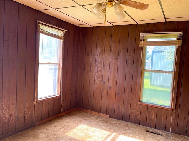 509 Whitcomb St, Lathrop, MO 64465 - carpeted empty room with healthy amount of natural light, ceiling fan, a paneled ceiling, and wood walls