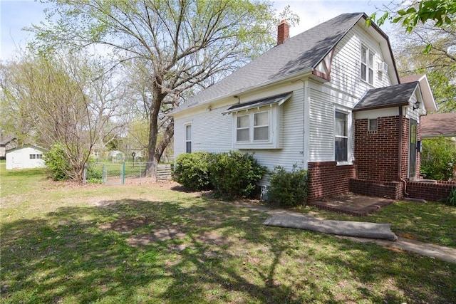 1221 Morgan Ave, Parsons, KS 67357 - view of property exterior featuring a lawn, a chimney, brick siding, fence, and a gate
