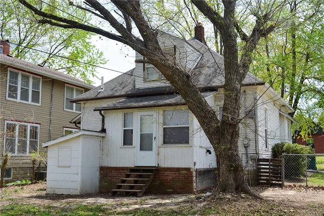 1221 Morgan Ave, Parsons, KS 67357 - back of property with a chimney, entry steps, a shingled roof, and fence