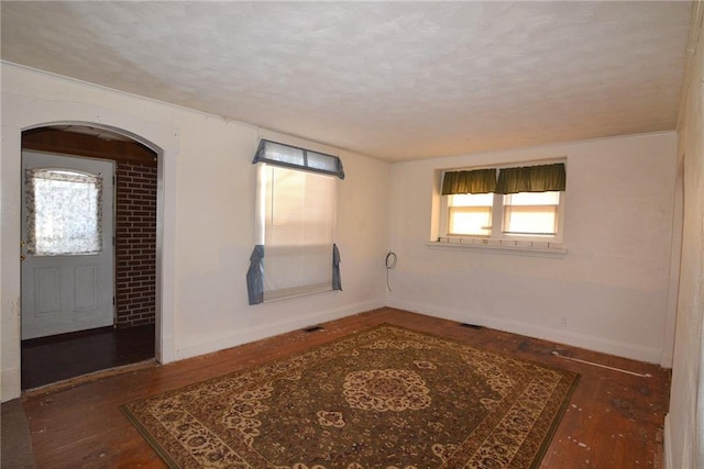 1221 Morgan Ave, Parsons, KS 67357 - empty room featuring baseboards, wood-type flooring, a textured ceiling, and arched walkways