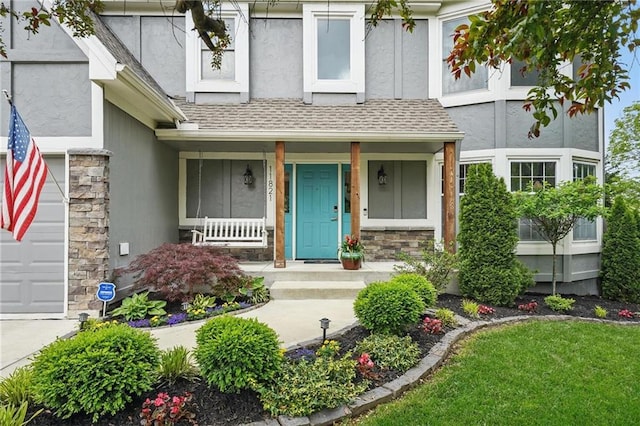 property entrance with stucco siding, a porch, stone siding, a garage, and roof with shingles