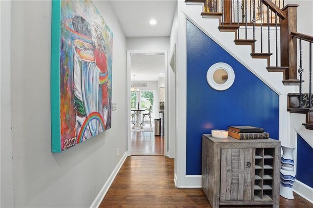 corridor featuring wood finished floors, stairs, baseboards, and recessed lighting