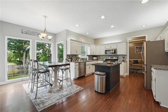 kitchen with appliances with stainless steel finishes, a kitchen island, plenty of natural light, decorative backsplash, and recessed lighting