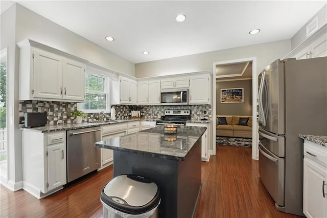 kitchen featuring stainless steel appliances, dark wood-style flooring, dark stone counters, white cabinetry, and recessed lighting