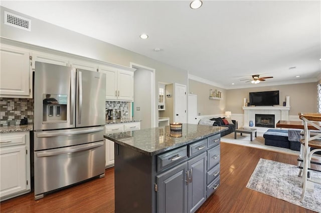 kitchen featuring stainless steel fridge, a ceiling fan, white cabinetry, tasteful backsplash, and a kitchen island