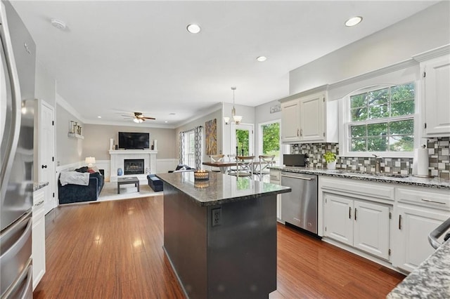 kitchen with stainless steel appliances, a sink, a ceiling fan, a glass covered fireplace, and a center island