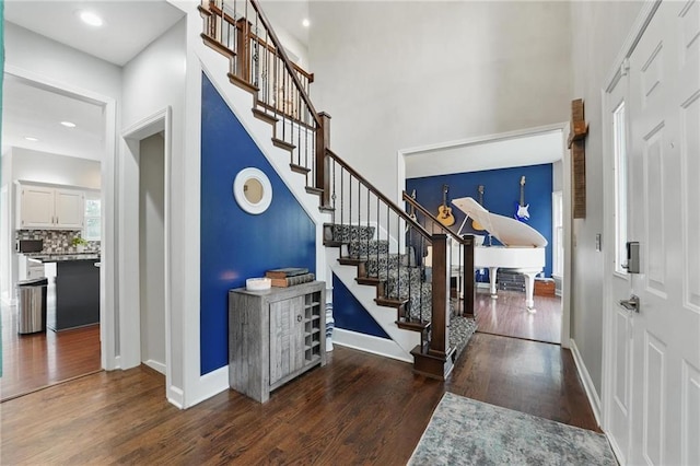 entrance foyer with wood finished floors, stairway, a towering ceiling, and baseboards