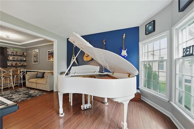 sitting room featuring wood finished floors, a bar, and baseboards