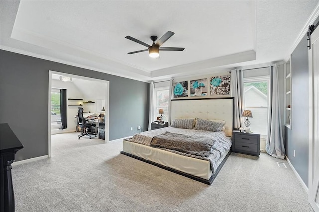 carpeted bedroom featuring a raised ceiling, an office area, multiple windows, and ornamental molding