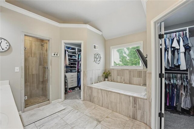 full bath featuring a stall shower, a bath, a spacious closet, vaulted ceiling, and ornamental molding