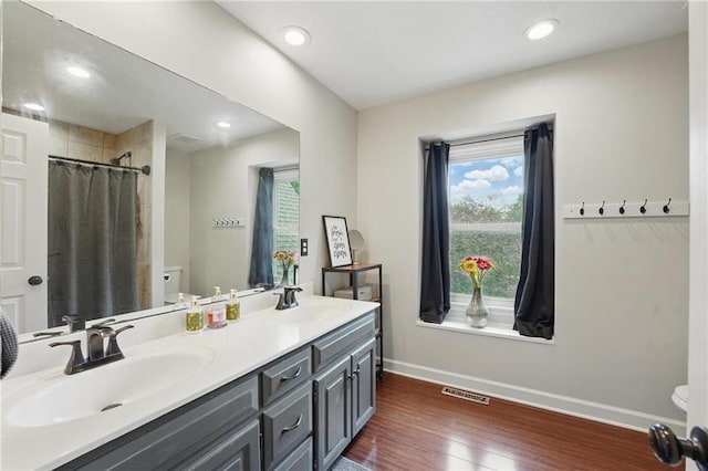 full bathroom with toilet, baseboards, wood finished floors, double vanity, and recessed lighting