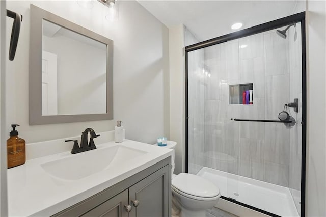 bathroom featuring a shower stall, toilet, and vanity