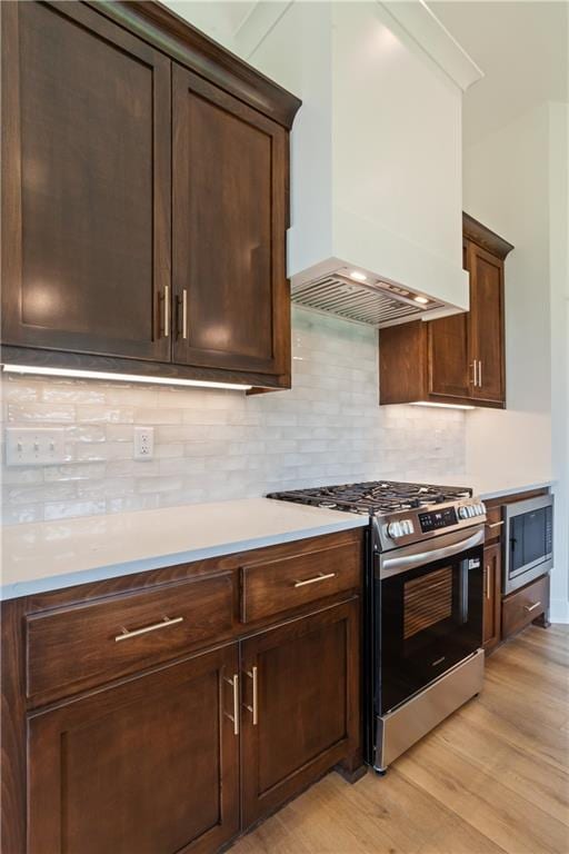 1604 Mulberry St, Pleasant Hill, MO 64080 - kitchen featuring appliances with stainless steel finishes, custom range hood, light wood-style flooring, light countertops, and backsplash